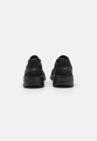 Baskets de sport noires avec une tige en mesh, un col rembourré et une semelle en caoutchouc, conçues pour le confort et la durabilité.