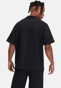 Svart bomullströja med avslappnad passform, korta ärmar och rundad halsringning; slät textur utan synliga mönster eller designs.