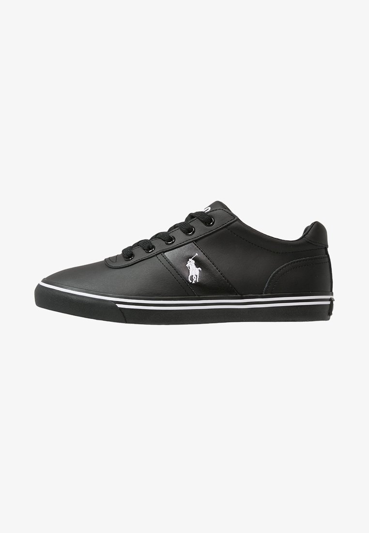 Black leather sneaker with a smooth texture, white accents, and a logo emblem on the side. Features a lace-up design and flat rubber sole.