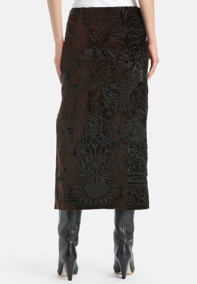 Rjava žametna krila z ročno vezenimi cvetličnimi motivi in izreznimi detajli, s snošeno silhueto in dolžino do kolen. V paru z črnimi visokimi škornji.