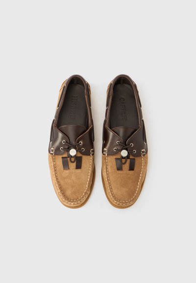 Καφέ δερμάτινα και ταμπά σουέντ παπούτσια τύπου boat με κορδόνια, στρογγυλό μεταλλικό διακοσμητικό και αντίθετη ραφή στην περιοχή των δαχτύλων.