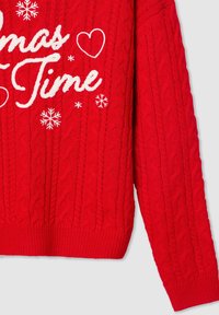 Czerwony sweter z dzianiny, ozdobiony wzorem w warkocze, ściśle przylegającymi mankietami oraz dołem, z białym haftem z tekstem świątecznym i wzorami płatków śniegu.