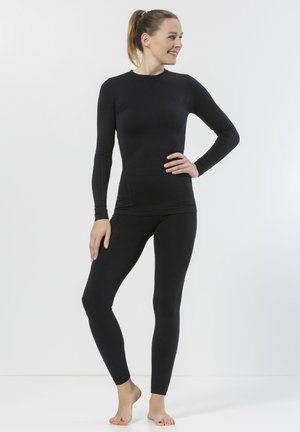 Zwarte lange mouw top met slim fit en gestructureerde mouwen, gecombineerd met zwarte strakke leggings, beide gemaakt van rekbare stof.