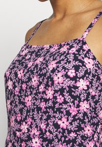 Blumenkleid mit pinken und weißen Blumen auf einem dunkelblauen Hintergrund, mit dünnen Schulterträgern und einem taillierten Oberteil-Design.