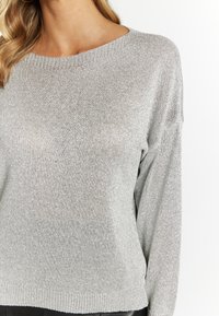 Ezüst, könnyű pulóver texturált kötésből, széles nyakkivágással és laza fazonnal, bordás mandzsettákkal és szegéllyel.