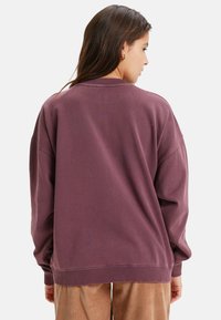 Overmaatse paarse sweatshirt van zacht materiaal, met ribgebreide manchetten en rand, met een relaxte pasvorm en een ronde hals.