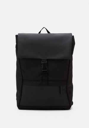 Sac à dos rectangulaire noir avec un rabat supérieur sécurisé par une boucle en plastique centrale et une petite poche avant zippée.