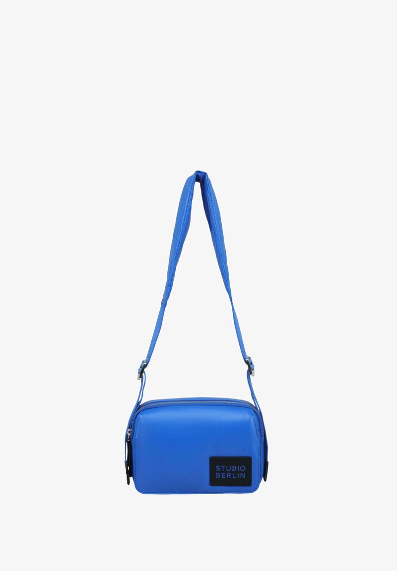 Modrá syntetická crossbody taška obdélníkového tvaru, se zipovým uzávěrem, nastavitelným popruhem a černou logem na přední straně.