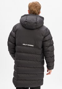 Černá péřová bunda s kapucí, prošívaným designem a elastickými manžetami. Bílé logo "HELly Hansen" na zadní straně.