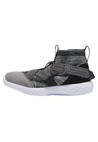 Czarno-szare buty sportowe z plecioną cholewką, wyściełanym kołnierzem, regulowanym paskiem oraz białą, teksturowaną podeszwą. Gładki szary detal na czubku buta.