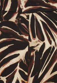 Tissu à motif abstrait de feuilles marron, noir et beige avec une couture visible courant verticalement près du centre.