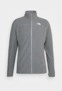 Szara polarowa kurtka z kołnierzem stójkowym, pełnym zamkiem błyskawicznym, kontrastującymi szarymi akcentami i bocznymi kieszeniami na zamek. Zawiera logo "The North Face".