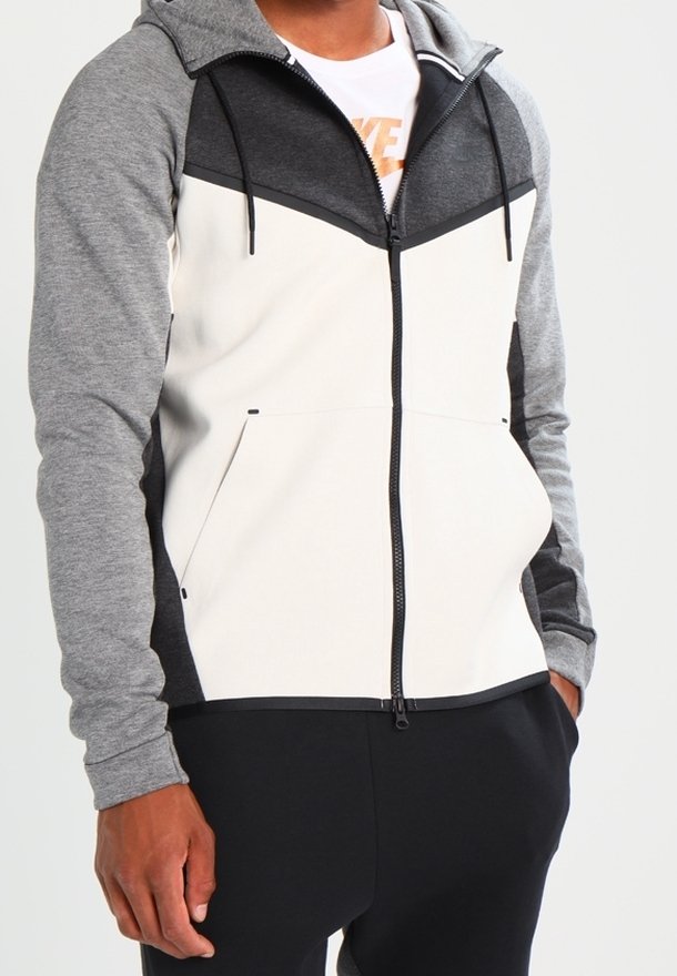 Hooded zip-up jacket with gray, black, and white color blocking. Features two front pockets and a sporty design in soft, textured fabric.
