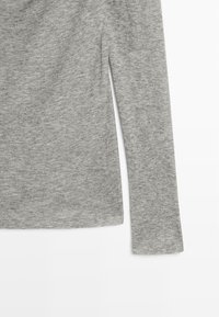 Szary, długi rękaw top wykonany z miękkiego materiału, z prostym okrągłym dekoltem i bocznymi rozporkami, prezentujący gładką strukturę bez wzorów.