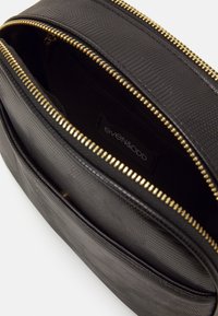 Czarna torebka ze skórzanej tekstury z złotymi zamkami. Posiada przestronną wnętrze oraz widoczną metkę wewnątrz. Liczne przegrody dla lepszej organizacji.