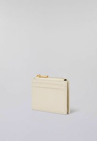 Portafoglio compatto realizzato in pelle testurizzata color crema, dotato di chiusura con zip e più scomparti per carte su un lato, con dettagli in hardware dorato.