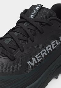 Μαύρο αθλητικό παπούτσι Merrell με υφασμάτινη υφή, χοντρή σόλα και μαύρα κορδόνια που διασταυρώνονται πάνω από τη μαξιλαρωμένη γλώσσα με το λογότυπο της μάρκας.