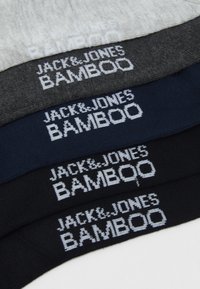 Quatre paires de chaussettes en blanc, gris foncé, marine et noir, avec "JACK&JONES BAMBOO" tissé en couleurs contrastées sur les bords.