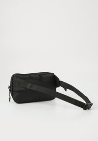 Compact black crossbody bag with adjustable strap and zipper closure, designed for hands-free carrying and everyday use.