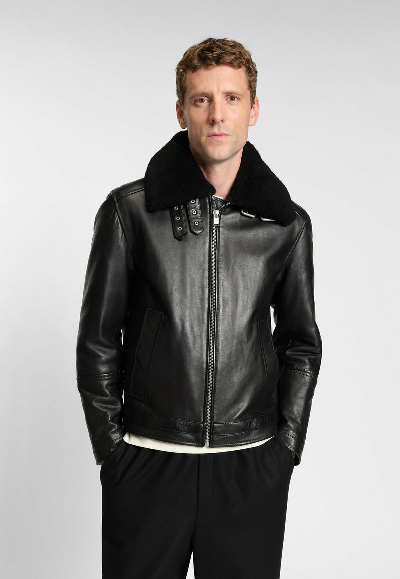Schwarze Lederjacke mit einer Kragen aus Schafsleder, ausgestattet mit einem Reißverschluss vorne, zwei Seitentaschen und subtilen Nähdetails.