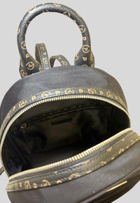 Zaino nero con manici in pelle, accenti dorati e rifiniture a motivo. Il compartimento principale presenta una chiusura con zip e foderatura in tessuto nero.