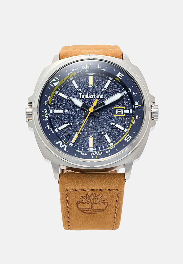 Heren Timberland horloge met een marineblauwe wijzerplaat, zilveren kast, gele secondewijzer, kompasmarkeringen, datumscherm en een tan lederen band met boomlogo.