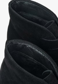 Czarne zamszowe botki za kostkę z teksturowanym skórzanym wnętrzem, charakteryzujące się zaokrąglonym brzegiem górnym oraz subtelnymi detalami w postaci przeszyć.