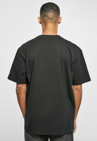 Tricou negru, cu guler rotund, mâneci scurte, fabricat din bumbac, având o textură netedă și o croială lejeră, fără grafică vizibilă.