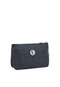 Black nylon pouch with a zip closure, rounded edges, and a circular silver hardware logo on the front. Smooth texture with minimal design.
