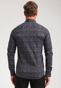 Camisa de botón azul marino con un patrón floral texturizado en color beige, mangas largas, cuello clásico y dobladillo curvado.