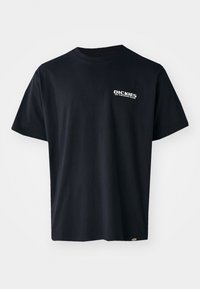T-shirt nera a maniche corte in cotone, con un logo testuale grafico bianco sulla parte sinistra del petto, dalla vestibilità dritta e con un'etichetta sul lato.