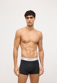 Czarne bokserki wykonane z miękkiego materiału, z geometrycznym wzorem, elastycznym pasem w talii z logo Calvin Klein oraz dopasowanym krojem.