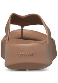 Sandali Crocs marroni con un design a piattaforma, suola spessa, una fascetta texturizzata e il logo "crocs" impresso sul lato.