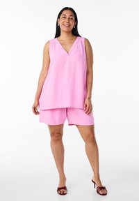 Top senza maniche rosa con scollatura a V e spalle arricciate, abbinato a pantaloni corti coordinati. Tessuto morbido, vestibilità ampia, design semplice e stile casual.