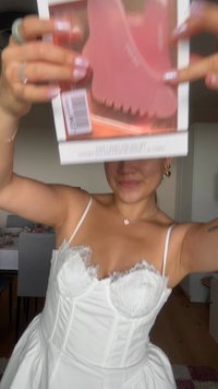 Rosa skor med rundad form och texturerad sula, hållna bredvid en produktlåda med en övergång från rosa till persika, visade med omsorg.