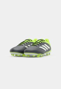 Schwarze und grüne Fußballschuhe mit einem schlanken Design, das eine strukturierte Oberfläche, weiße Akzentstreifen und geformte Stollen an der Sohle umfasst.