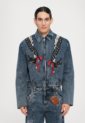 Kurz geschnittene Jeansjacke mit geflochtenem Stickmuster in Schwarz, Rot und Weiß. Verfügt über einen Reißverschluss und eine taillierte Passform. Abgenutzte Jeansoberfläche.