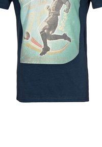 Námořnické modré bavlněné tričko s vintage potiskem fotbalisty, texturovaná grafika s jemně zelenými a červenými akcenty.