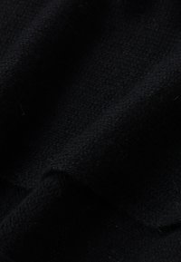 Tessuto intrecciato nero con una superficie leggermente strutturata, che mostra morbide pieghe e un colore ricco e profondo. Nessun motivo o accento è visibile.