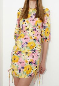 Blommig kort klänning i gult med rosa och lila accenter, med puffärmar, rynkor på sidorna och dragsko.