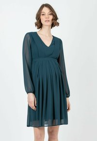 Türkisfarbiges Chiffon-Kleid mit V-Ausschnitt, langen transparenten Ärmeln, plissiertem Rock und Empire-Taille. Verfügt über eine fließende Silhouette und weiche Textur.