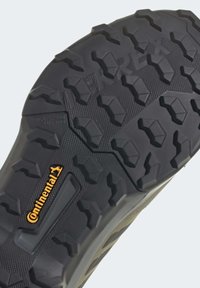 Černá gumová podrážka s hlubokým, agresivním dezénem, texturovaným povrchem a oranžovým logem Continental blízko paty.