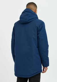 Navy blue, long puffer jacket with a hood, featuring a smooth exterior and elastic cuffs; straight cut and minimalistic design.