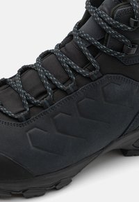 Schwarze Wanderschuhe aus strukturiertem Material, mit dunkelblauen gemusterten Schnürsenkeln, robuster Sohle und schrägem seitlichem Design für zusätzlichen Grip.
