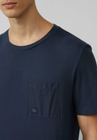 Marineblauw crew-neck t-shirt van katoen, met een linkse borstzak met een subtiel logo en korte mouwen. Gladde textuur.