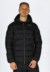 Svart pufferjacka med dragkedja fram, huva, quiltat mönster och logotyp på bröstet. Har två sidofickor och elastiska ärmslut.