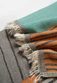 Coperta in tessuto caratterizzata da colori turchese, arancione e grigio. Il design include strisce e bordi frangiati. Texture liscia, tessuto tessuto.