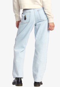 Světlemodré džíny rovného střihu s dvěma zadními kapsami, které mají barevnou výšivku. Hladká denimová textilie, s ohrnutím na kotnících.
