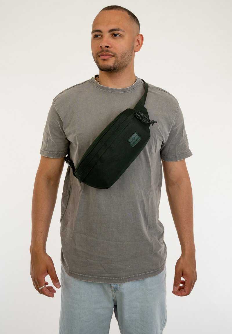 Borsa a tracolla verde con forma rettangolare, realizzata in tessuto. Presenta una chiusura con zip e una tracolla regolabile per indossarla a tracolla.