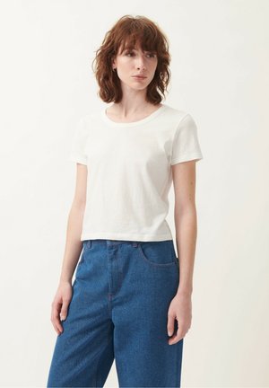 Witte cropped t-shirt met een ronde halslijn en korte mouwen, gecombineerd met hoog-wijde blauwe denim broek met rode stiksels.